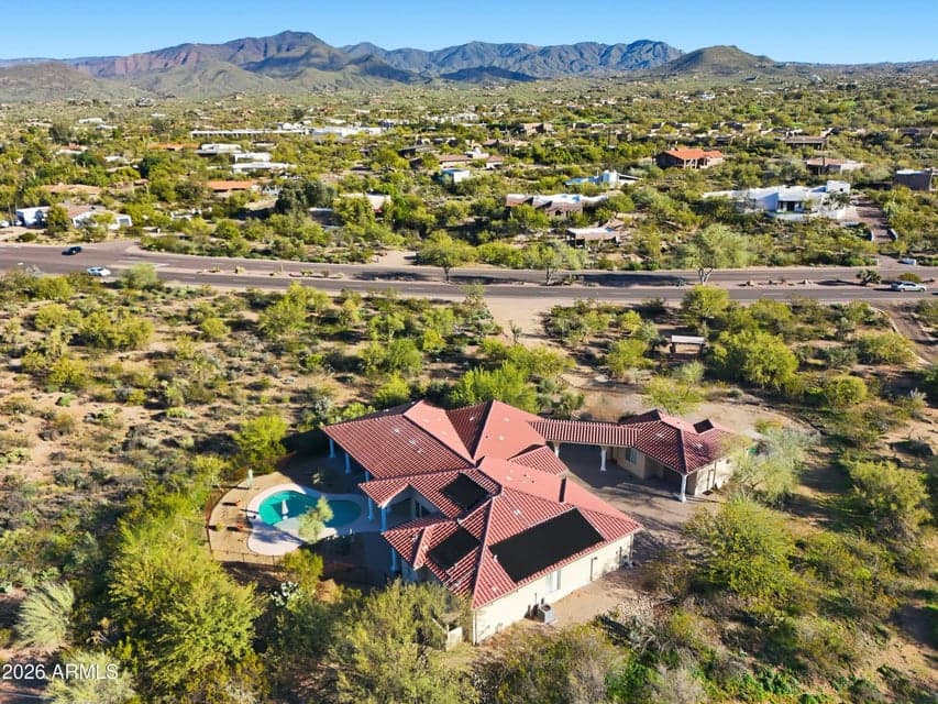 Aerial view highlighting the home’s expansive lot, pool, and panoramic mountain and desert views.