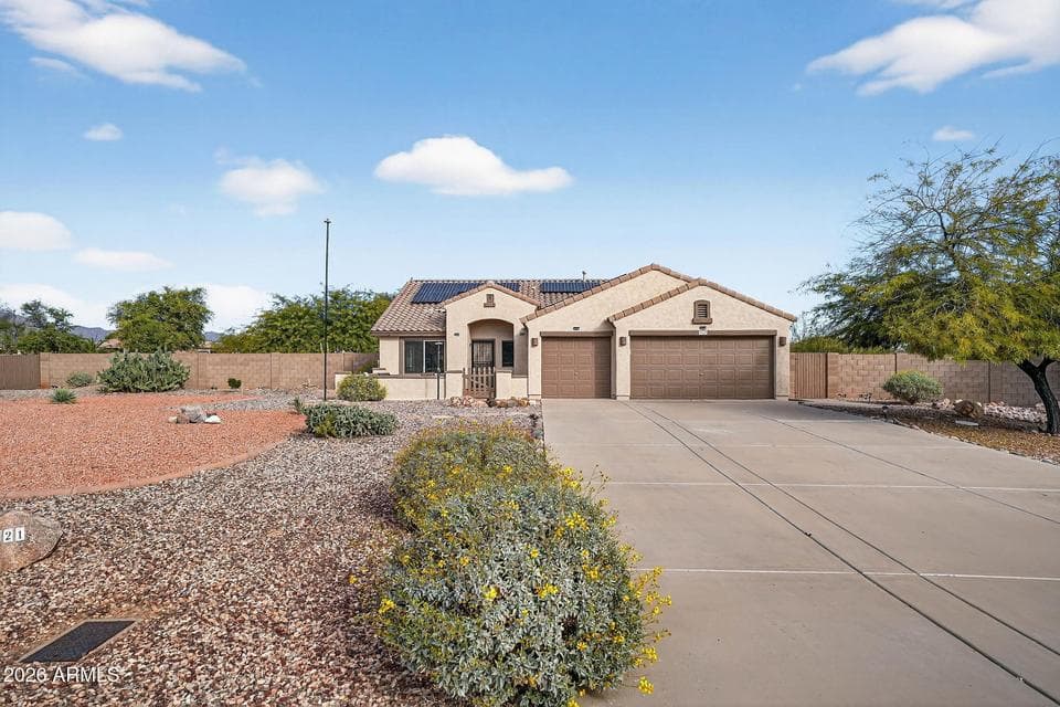 Beautiful front exterior of this gated Litchfield Park home featuring a wide driveway, mature desert landscaping, and solar panels for energy efficiency. This spacious 1-acre property offers standout curb appeal and room to park, host, and enjoy Arizona outdoor living.