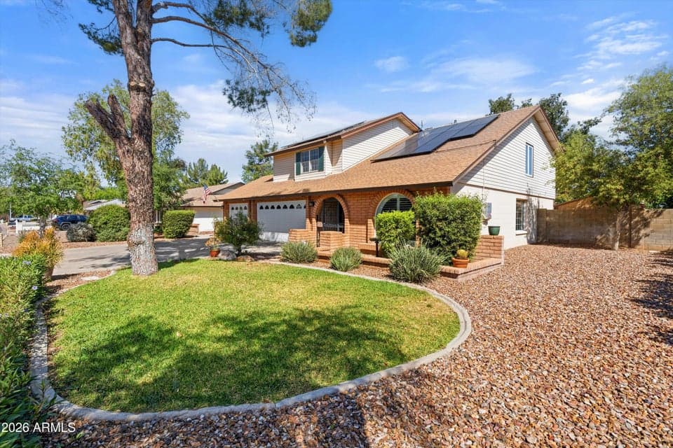 Beautiful front elevation showcasing mature landscaping, lush green lawn, desert-friendly landscaping, and a spacious three-car garage. This well-maintained Glendale home offers outstanding curb appeal with owned solar panels and an inviting exterior in the desirable Bellair community.