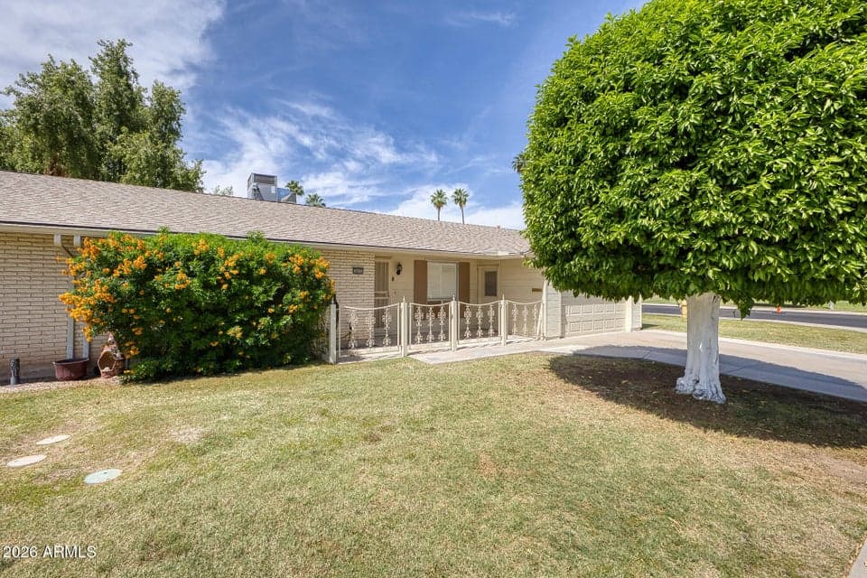 Beautiful front courtyard features mature landscaping, a manicured lawn, and a covered entrance that enhances the welcoming curb appeal of this well-maintained Sun City home.
