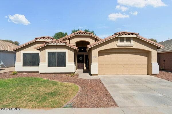 Striking front exterior of this Goodyear property for sale in Canyon Trails, featuring Southwestern-inspired architecture, a tile roof, two-car garage, covered entry, mature landscaping, and warm evening curb appeal. This digitally altered twilight presentation highlights the home's attractive architectural lines and welcoming street presence.