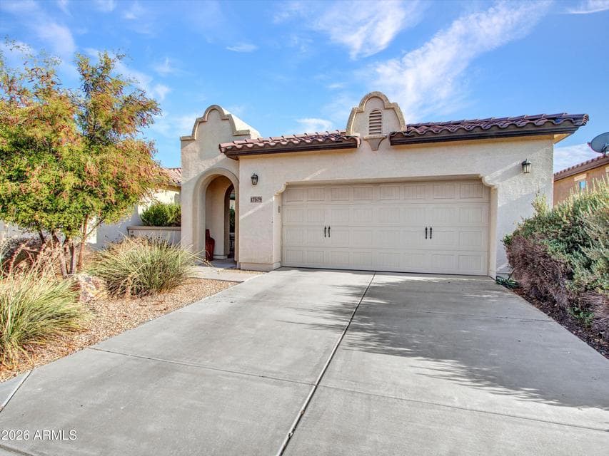 Welcoming front exterior of this CantaMia home featuring a clean stucco finish, attached garage, and spacious driveway. Low-maintenance desert landscaping enhances curb appeal.