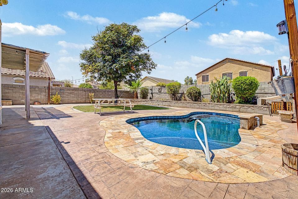 Inviting backyard retreat featuring a sparkling private pool, expansive travertine-style decking, mature landscaping, and plenty of space for outdoor entertaining and relaxing.