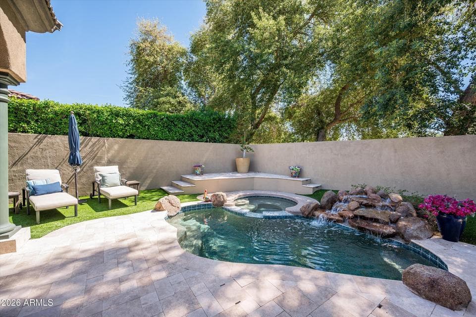 Tranquil backyard pool with waterfall feature, spa, and updated tile, offering a the perfect experience for relaxing and enjoying Phoenix outdoor living.