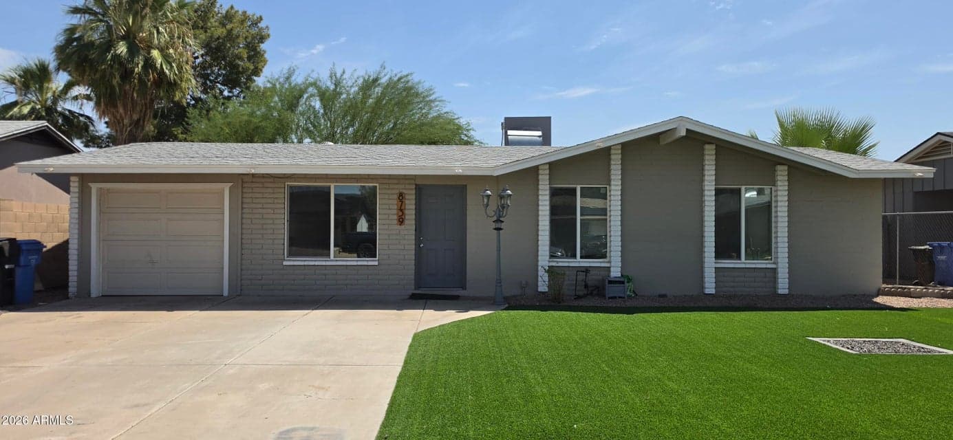 Charming single-family home featuring classic mid-century modern curb appeal, a low-maintenance artificial turf front lawn, a spacious concrete driveway, and a single-car garage.