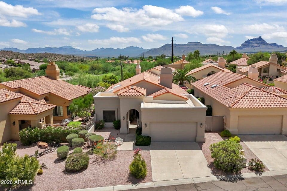 Stunning elevated view of this desirable patio home showcasing its classic tile roofline, attached garage, and picturesque mountain backdrop.