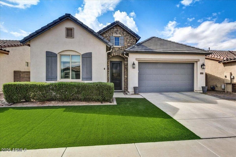 Freshly painted exterior home featuring manicured landscaping, custom curbing, and low-maintenance synthetic turf.
