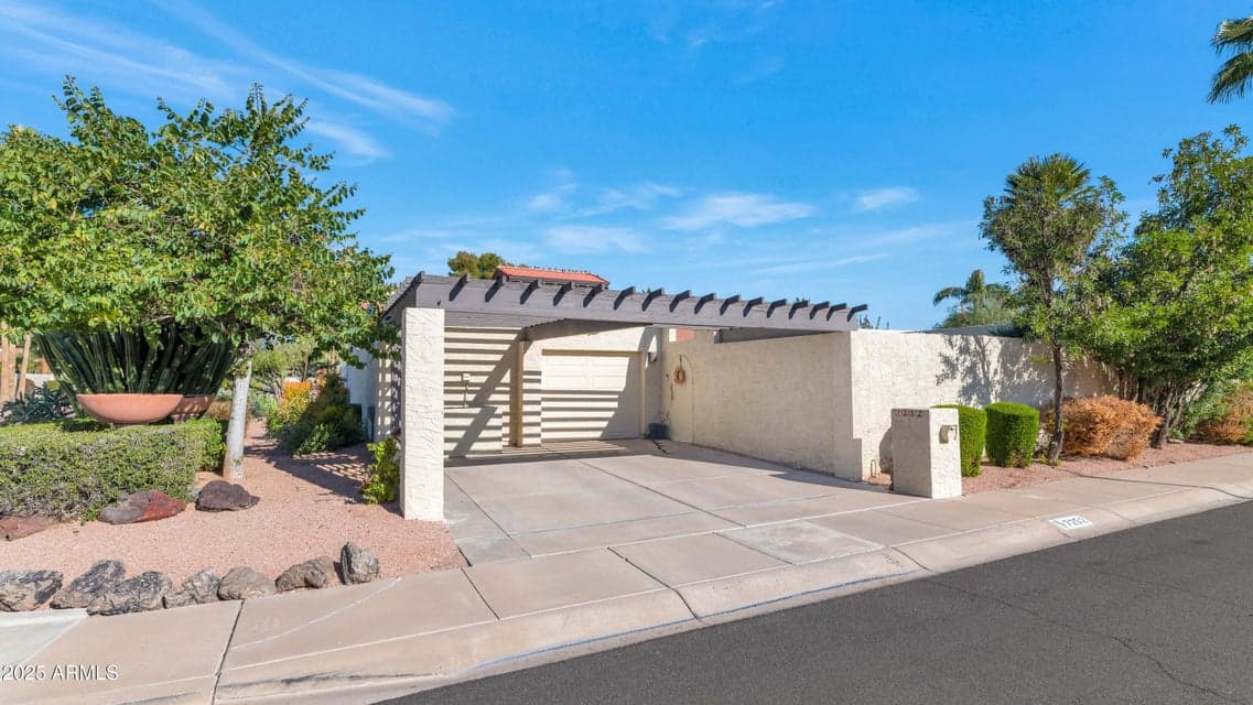 Bright Scottsdale dining space featuring a statement chandelier, wood-style flooring, and seamless flow into the updated kitchen. Large sliding glass doors provide natural light and easy access to the private patio, enhancing indoor-outdoor living.
