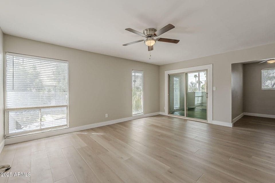 Bright open living room with wide-plank flooring, neutral paint, and sliding glass doors leading to the private patio. Updated finishes create an inviting Phoenix living space ideal for relaxing or entertaining.