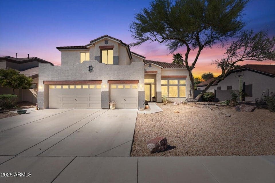 Beautiful Chandler home showcased at twilight with warm interior lighting, desert landscaping, and inviting curb appeal. Features a spacious driveway, multi-car garage, and elegant architectural design.