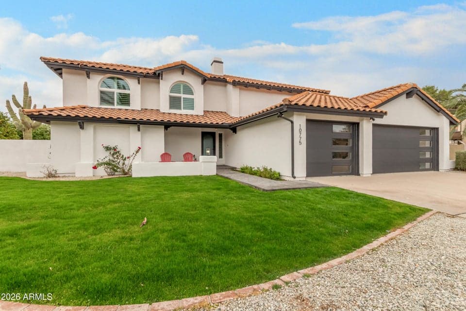 Beautifully updated Scottsdale home featuring fresh exterior finishes, a tile roof, modern garage doors, and a lush green lawn. This impressive curb appeal showcases extensive renovations and welcoming outdoor living spaces.