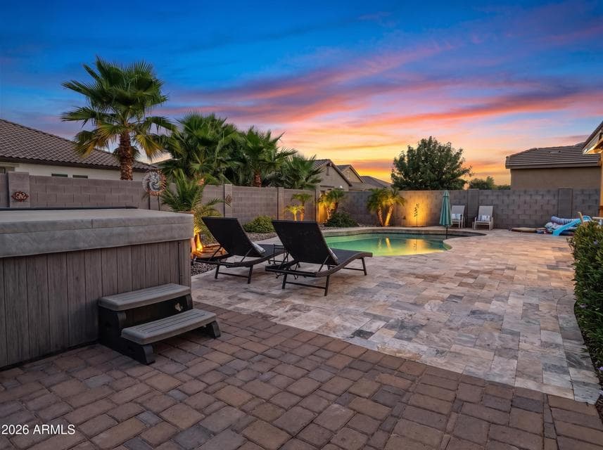 Relax or entertain around the heated pool featuring a new travertine pool surround, above-ground spa, generous patio space, and low-maintenance desert landscaping.