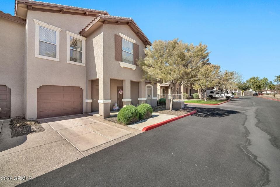Attractive condominium exterior with an attached garage, welcoming front entry, and professionally maintained landscaping within the gated Renaissance Villas community in Litchfield Park.