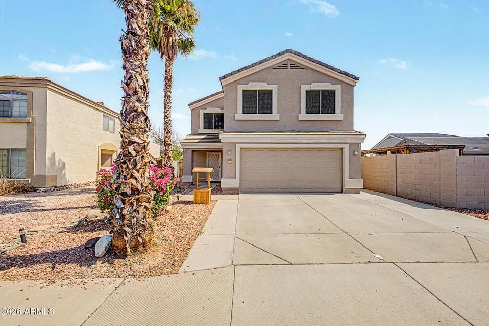 Front exterior — Two-story stucco home with tile roof, three-car-width driveway, and mature palm trees framing the entry.