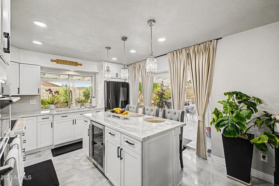 Bright remodeled kitchen with white all new cabinetry, a spacious center island, stainless steel appliances, modern lighting, and plenty of natural light.