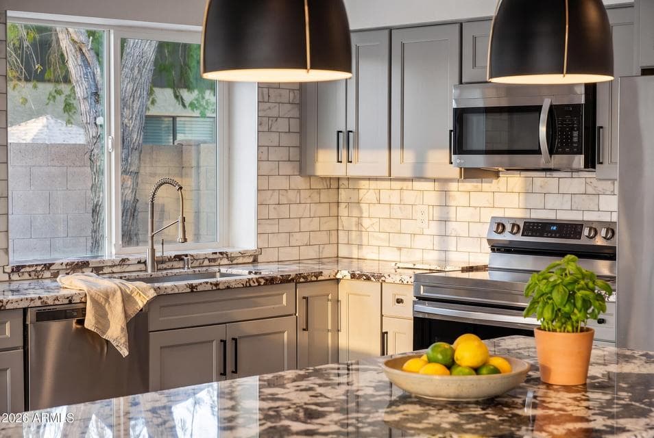 This kitchen features a classic marble subway tile backsplash, custom cabinetry, and stainless steel appliances beneath dramatic quartzite countertops. This move-in ready Scottsdale home offers a stylish, updated kitchen ready for everyday cooking and entertaining.