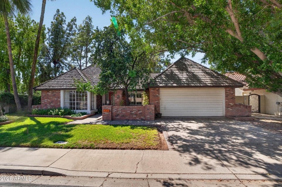 Lovingly maintained single-level curb appeal in the heart of Dobson Ranch featuring mature green landscaping, a welcoming brick-accented entry, and classic curb appeal at 2656 S Salida Del Sol in Mesa, Arizona.